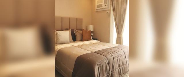 A neatly made bed featuring white sheets and a tan comforter, creating a warm and inviting atmosphere.