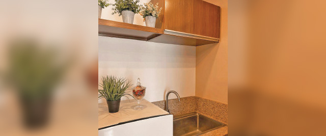 A modern kitchen featuring a sink, refrigerator, and a wine glass on the counter, showcasing a cozy dining atmosphere.